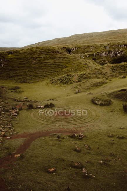 Gebirgstal mit grünem Gras und geheimnisvollem Spirallabyrinth aus Steinen in Fairy Glen — Stockfoto