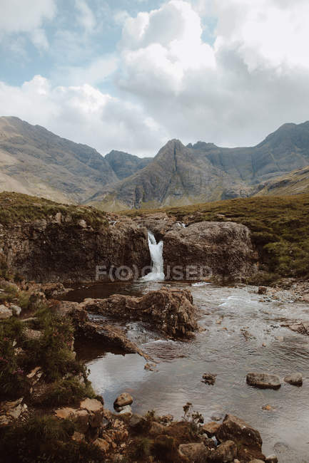 Vista deslumbrante de altas montanhas nuas e água caindo da rocha em Fairy Pool durante o dia — Fotografia de Stock