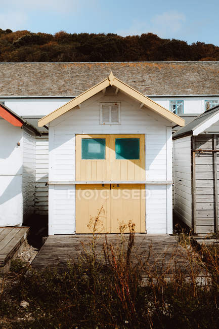 Beach huts of different color with closed doors by woods under blue sky on daytime — Stock Photo