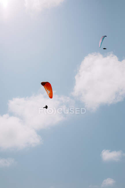 Von unten fliegen Menschen mit bunten Gleitschirmen bei bewölktem Himmel in der Nähe von Durdle Door am Tag — Stockfoto