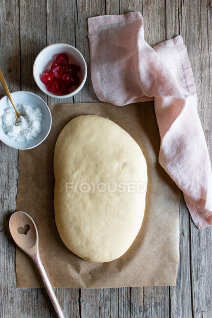 From above dough on baking paper and ingredients prepared for cooking Spanish pie called coca San Juan on wooden table — Stock Photo