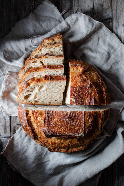 Morceaux de pain frais savoureux tombant sur la serviette sur la table sur fond noir — Photo de stock