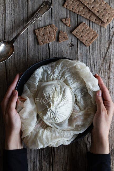 Oben knusprige Cracker und Löffel in der Nähe von Teller mit frischem Labneh-Käse auf Holztisch platziert — Stockfoto