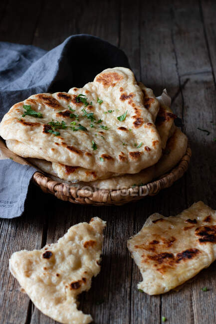 Teller mit leckerem Naan-Brot und Stoffserviette auf verwittertem Holztisch — Stockfoto