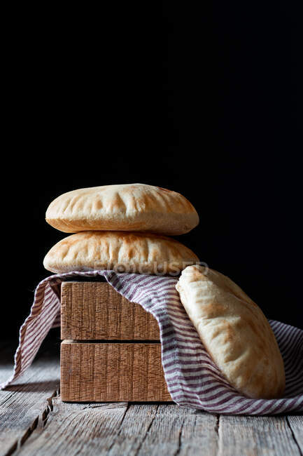 Свіжий піта плоский хліб, розміщений на серветці та дерев'яних блоках на сільському столі на чорному тлі — стокове фото