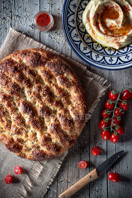 From above loaf of Ramazan pidesi placed near fresh tomatoes and spices on lumber tabletop — Stock Photo