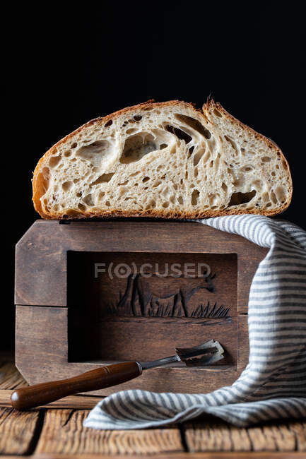 Pan fresco partido a la mitad con semillas contra pared de madera - foto de stock