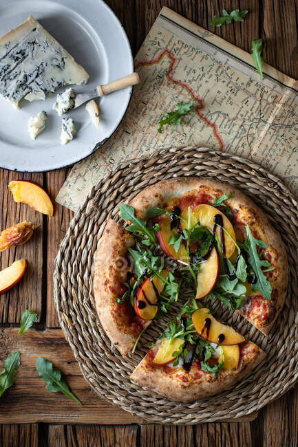 Deliciosa pizza fresca de verano colocada en la mesa de madera en la cocina rústica - foto de stock