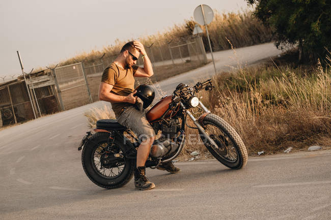 Homme fort assis sur une moto dans le désert — Photo de stock
