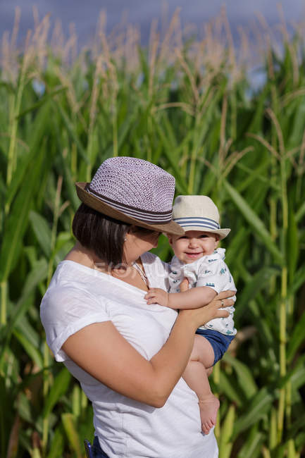 Adorable mère et enfant à portée de main jouissant et riant dans le champ — Photo de stock