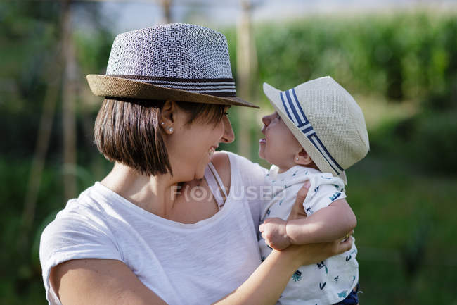 Чарівна мати і дитина під рукою насолоджується і сміється в полі — стокове фото