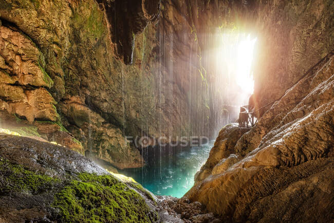 Caverna tropical cênica com rio subterrâneo e caminho com trilhos à luz solar — Fotografia de Stock
