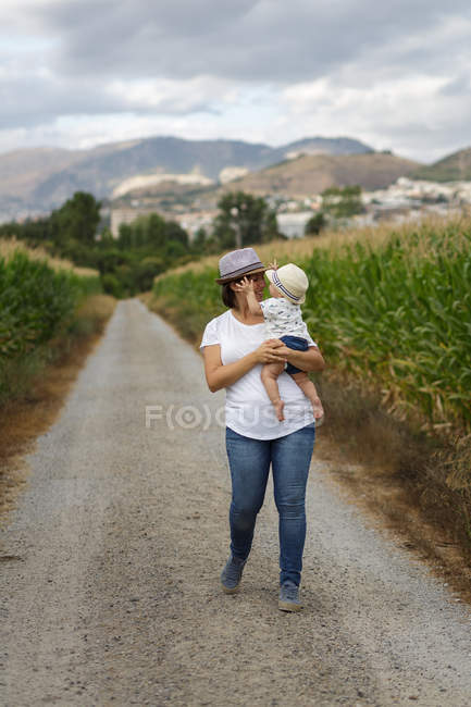 Adorable madre e hijo a la mano disfrutando y riendo en el campo - foto de stock