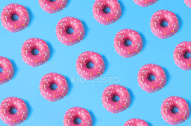 Padrão sem costura de rosquinhas doces rosa colocados no fundo azul — Fotografia de Stock