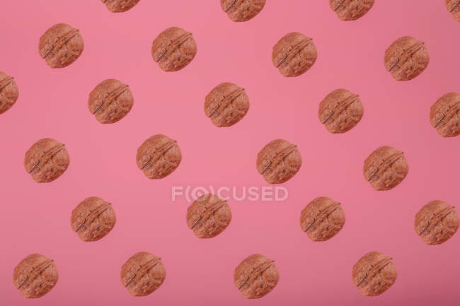 Візерунок, розташований з гофрованих стиглих волоських горіхів, ізольований на яскраво-рожевому фоні — стокове фото