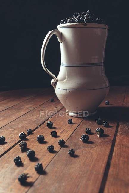 Vintage jag with ripe blackberries on wooden table — Stock Photo
