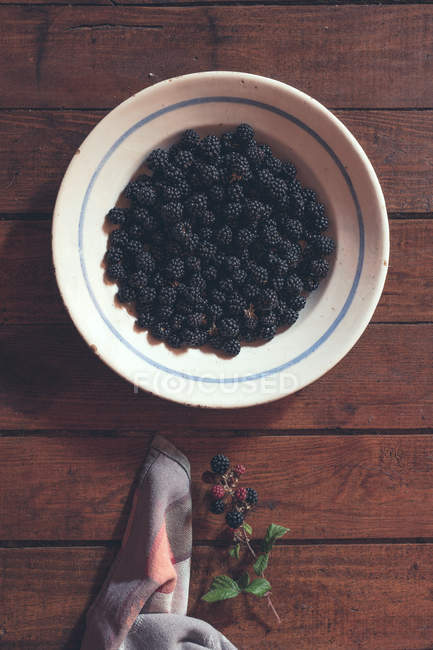 Ripe blackberries garnished by leaves and napkin in bowl — Stock Photo