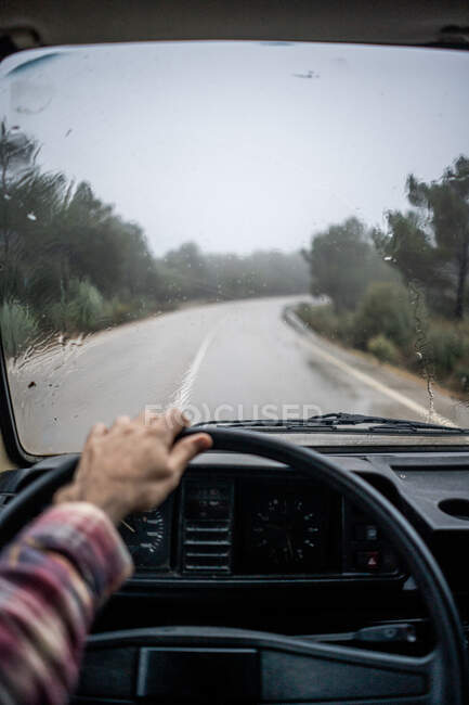 Autista guida auto lungo il sentiero rurale a foresta sotto la pioggia — Foto stock