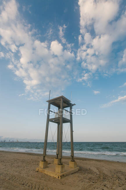Construcción de observación en playa de arena con huellas de ruedas por mar ondulado en día nublado - foto de stock