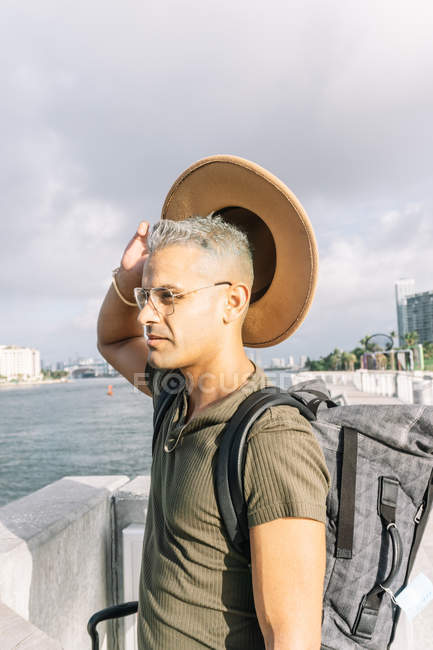 Профіль молодого чоловіка в окулярах, що виймає капелюх — стокове фото