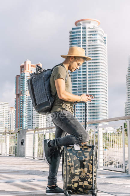 Человек в шляпе и рюкзаке ищет направление по телефону — стоковое фото