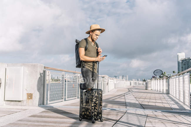 Чоловік в капелюсі і рюкзаку шукає напрямок по телефону — стокове фото