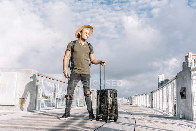 Viaggiatore uomo con un cappello a piedi con valigia in strada — Foto stock