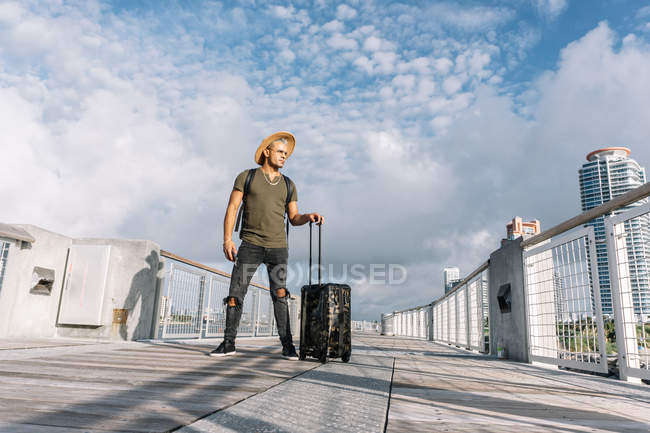 Hombre viajero con sombrero caminando con maleta en la calle. - foto de stock