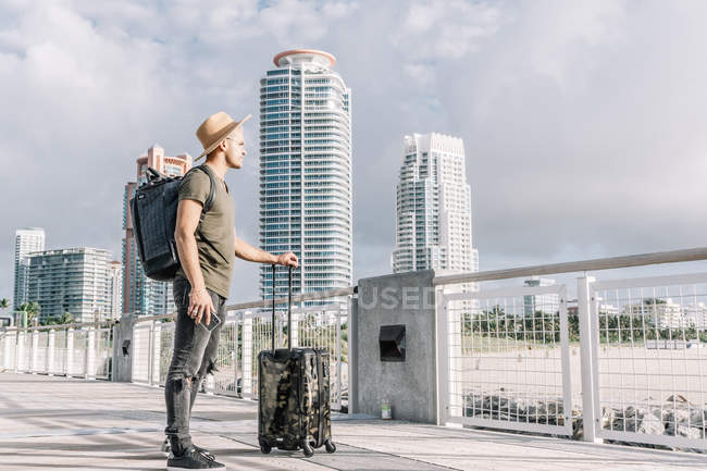 Jeune homme debout avec sa valise et profitant de la vue avant le départ — Photo de stock