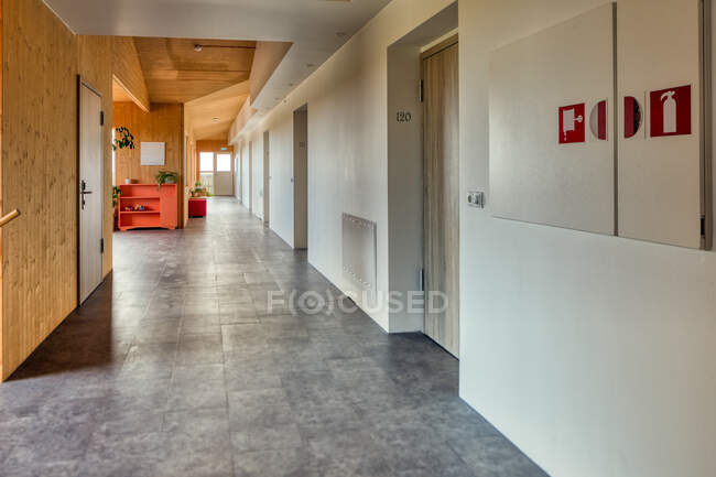 Pulito accogliente corridoio luminoso con pareti in legno e bianco e pavimento in piastrelle grigie nella moderna e spaziosa hall dell'hotel che soddisfa tutti gli standard internazionali di ospitalità — Foto stock