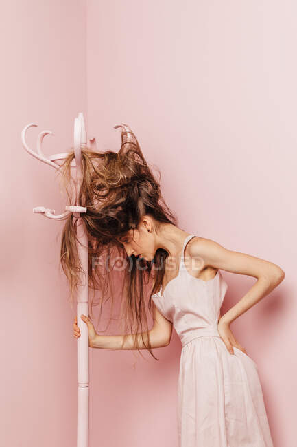 Передній вид дівчини-підлітка з заплутаними волоссям на рожевому фоні — стокове фото