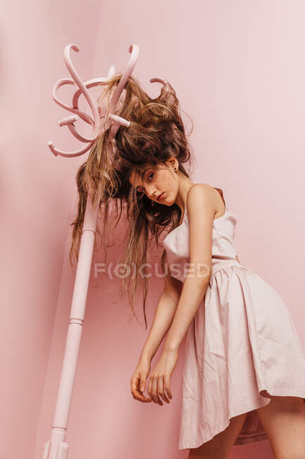 Вид спереди на девочку-подростка с запутанными волосами на розовом фоне — стоковое фото
