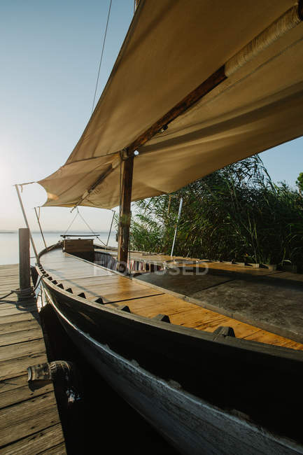 Barco amarrado por muelle de madera - foto de stock