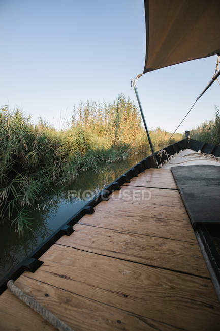 Holzverkleidung des neuen sauberen Schiffes an einer ruhigen, sonnigen Lagune, umgeben von Büschen in Valencia — Stockfoto