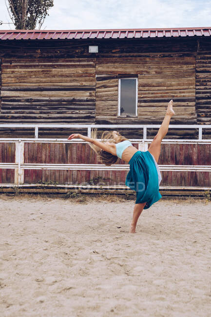 Flexible woman in colorful skirt dancing at rural paddock — Stock Photo
