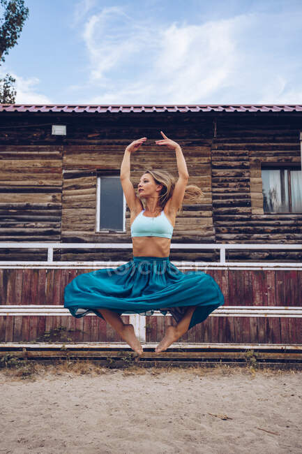Mujer flexible en falda colorida bailando en el paddock rural - foto de stock