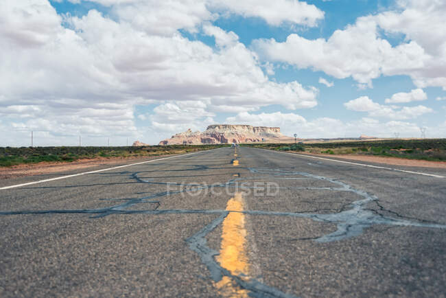 Landstraße auf staubigem Feld mit Hochspannungsleitung und abgelegener Gebirgskette in der Route 66, USA — Stockfoto