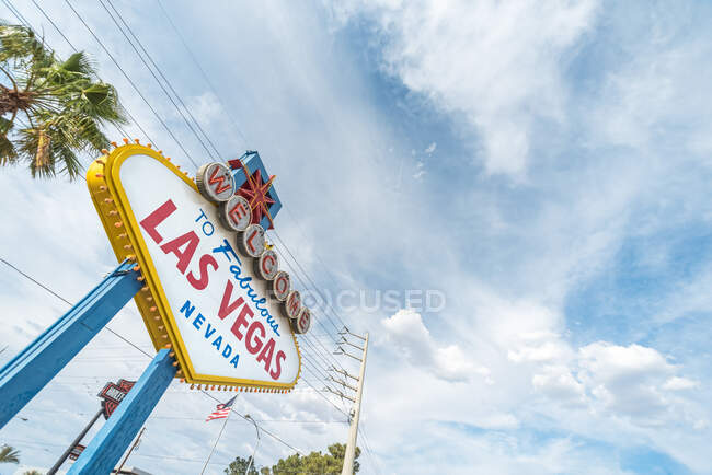 Bajo ángulo de tráfico colorido ciudad signo por palmera sobre cielo nublado en Las Vegas, Nevada, EE.UU. - foto de stock
