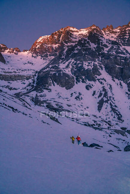 Vista posteriore di persone irriconoscibili in giacca colorata con zaino e attrezzatura da trekking che camminano in pendenza alla luce del giorno — Foto stock