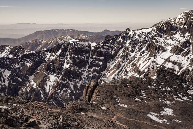 Затишні скелясті схили гірського ланцюга з сніжними вершинами в денний час. — стокове фото