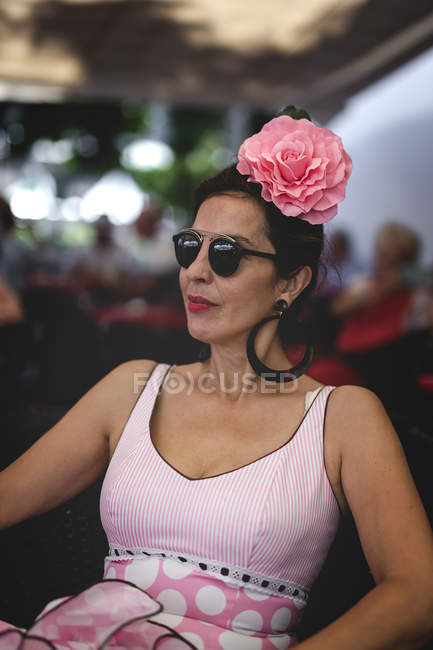 Eccentric woman in colorful pink costume sitting on summer street — Stock Photo