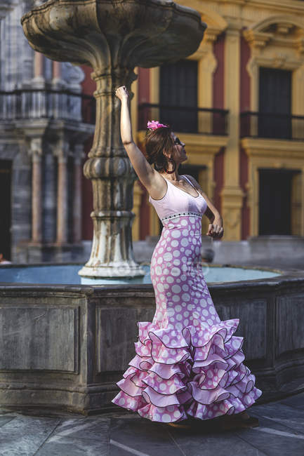 Eccentrico donna deliziata in costume rosa colorato sorridente e danzante da fontana nella giornata di sole — Foto stock