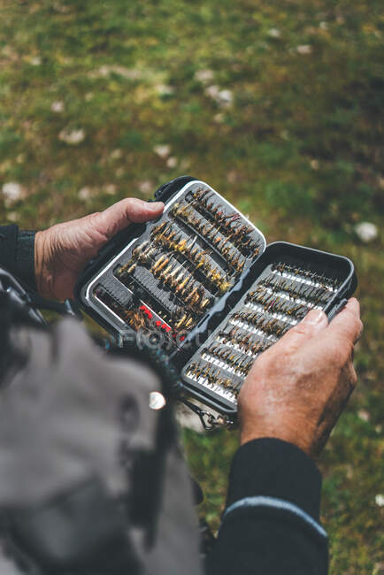 Человек в возрасте посевов показывает организованные приманки и крючки, стоя на сельской улице — стоковое фото