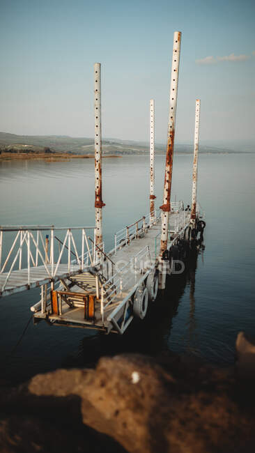 Old rusty pier with distant tourist located near peaceful sea water during dusk — Stock Photo