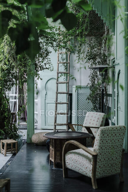 Старая деревянная лестница и кресла, расположенные у входа в традиционное арабическое здание с зелеными стенами в Марракеше, Моррехо — стоковое фото