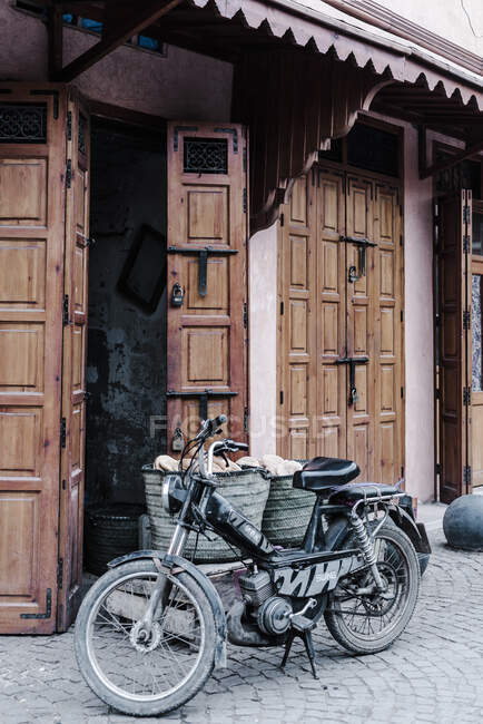 Мотоцикл Shabby retro припаркований біля дерев'яних дверей на вулиці Марракеша, Марокко. — стокове фото