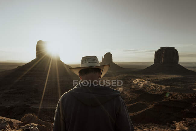 Back view of touristic person in hat watching at ancient old buildings in desert on sunlight in USA — Stock Photo