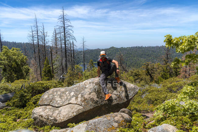 Entspannter Wanderer ruht sich auf großem Felsen im Wald aus — Stockfoto