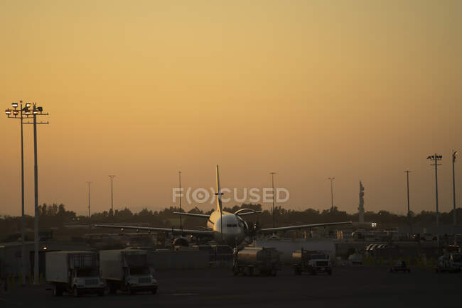 Aeronaves distantes e brilhantes rodeadas de veículos de serviço no aeródromo ao pôr-do-sol nos EUA — Fotografia de Stock