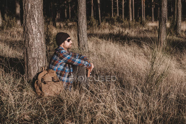Relaxed tourist resting by tree in forest — Stock Photo